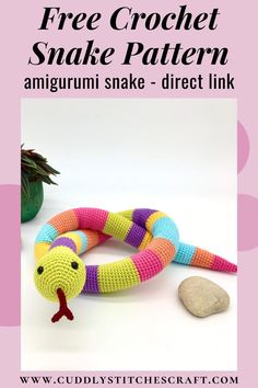 the crochet toy snake is sitting next to some rocks