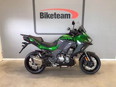 a green and black motorcycle parked in front of a biketeam logo on the wall