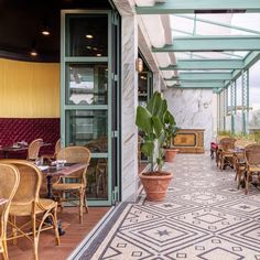 an outdoor dining area with tables and chairs on the outside patio, along with potted plants