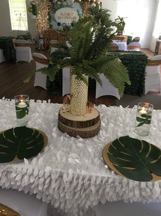 a table topped with plates covered in green plants and greenery next to a vase filled with flowers