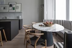 a bowl of fruit sits on a marble table in the middle of a room with black and white striped chairs