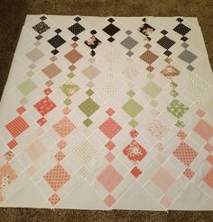 a quilted table topper on the floor in front of a brown and white carpet