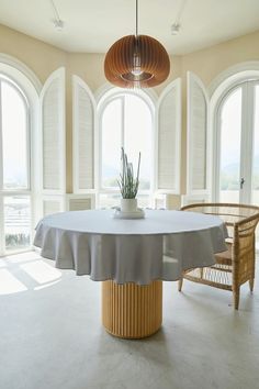 a dining room table with a plant in the center surrounded by chairs and round windows