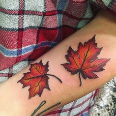 a woman's arm with two red maple leaves on the left side of her body