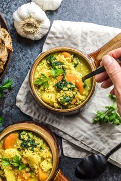 two bowls filled with soup and vegetables on top of a table next to some bread