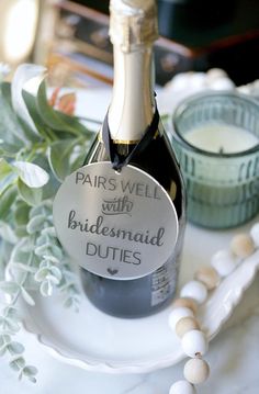 a bottle of champagne sitting on top of a white plate next to some flowers and candles