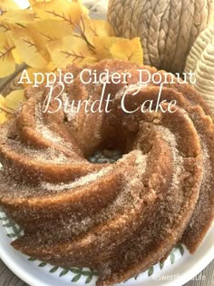 an apple cider donut bundt cake on a plate with autumn leaves in the background