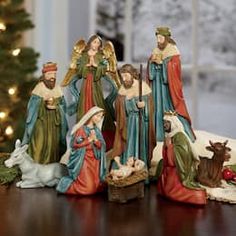 a group of figurines sitting on top of a table next to a christmas tree