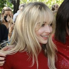 two women standing next to each other in front of a group of people with cell phones