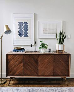 a living room with two framed pictures on the wall and a wooden dresser in front of it