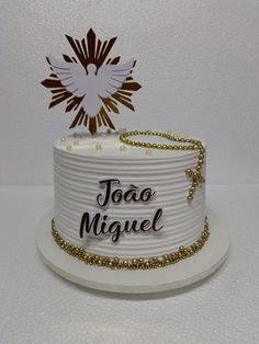 a white cake with gold decorations and the words joao miguel on it's side