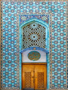 an ornate door and window in the middle of a building with blue tiles on it