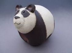 a small ceramic panda bear sitting on top of a table next to a black and white wall