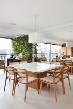 the dining room table is surrounded by wooden chairs and white tile flooring, along with large windows overlooking cityscape