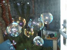 soap bubbles floating in the air near a christmas tree and window sill with snow on it