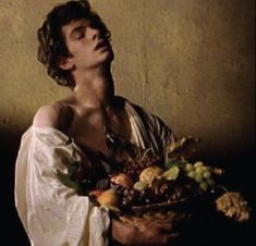 a man with his eyes closed holding a basket of fruit and vegetables in front of him