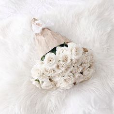 a bouquet of white flowers is laying on a furry surface with a hat on top