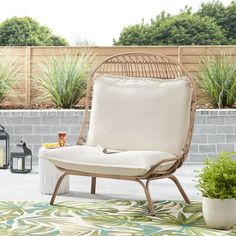 a chair sitting on top of a rug next to a table with candles and plants