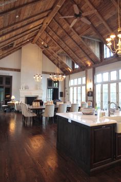 a large open concept kitchen and dining room with wood floors, high ceilings, and chandeliers hanging from the ceiling