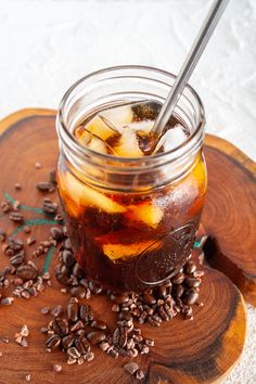 a glass jar filled with iced coffee sitting on top of a wooden coaster covered in seeds