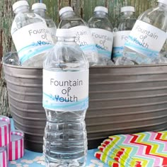 several bottled water bottles sitting on top of a table next to a bucket full of wrapped presents