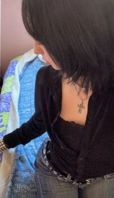 a woman with a cross tattoo on her chest looking down at something in front of her