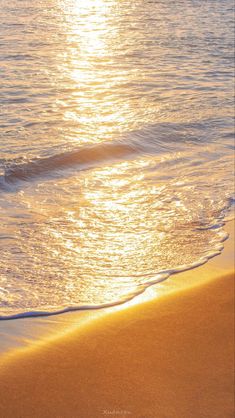 the sun is setting over the ocean with waves coming in on the sand and water