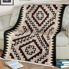 a black and white quilt sitting on top of a couch next to a book shelf