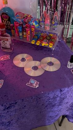 a purple table topped with cd's and confetti on top of it