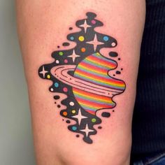 a colorful saturn tattoo on the right arm and leg, with stars around it in black ink