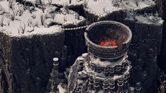 a large metal bucket sitting on top of a snow covered tree stump in the middle of winter