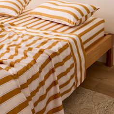 an orange and white striped bed spread on top of a wooden headboard with two pillows