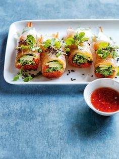 a white plate topped with sushi rolls and dipping sauce