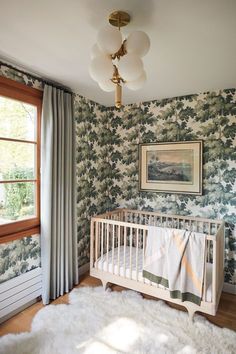 a baby's crib in the corner of a room with floral wallpaper