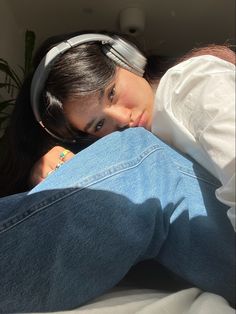 a woman laying on top of a bed wearing headphones