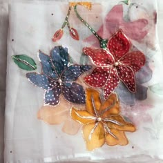 three different colored flowers on a piece of cloth