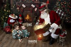 a little boy sitting next to santa claus in front of a fire place with presents