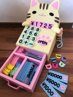 a toy cat sitting in a pink box filled with lots of numbers and magnets