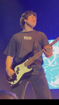 a young man playing a bass guitar on stage