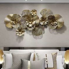 a white bed topped with lots of pillows next to a wall mounted art piece on the side of it