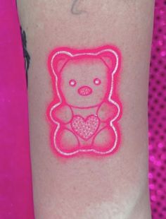 a pink teddy bear with a heart tattoo on the arm