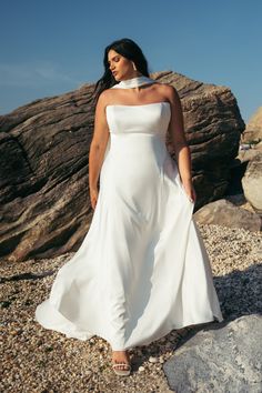 a woman in a white dress standing on rocks