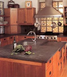 a kitchen with wooden cabinets and an island in front of a stove top oven that has wine bottles on it