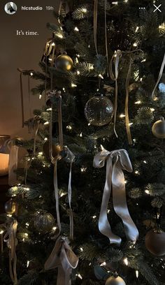 a christmas tree with ornaments and lights on it's branches is decorated in gold, silver and white