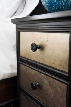 a black dresser with two drawers and a blue pillow on top of the headboard