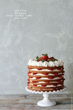 a cake with white frosting and strawberries on top sitting on a wooden table