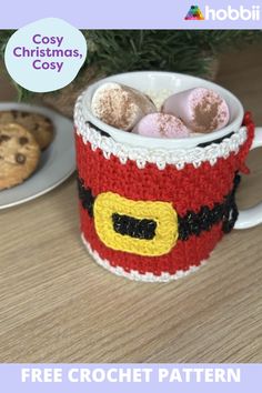 there is a crocheted mug with cookies in it on the table next to a cookie