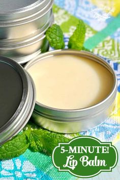 four tins of lip balm with mint leaves around them on a colorful cloth