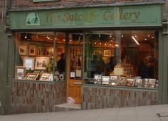 a store front with many items on display in it's windows and people walking by