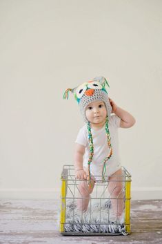 a baby sitting in a basket with a hat on top of it's head